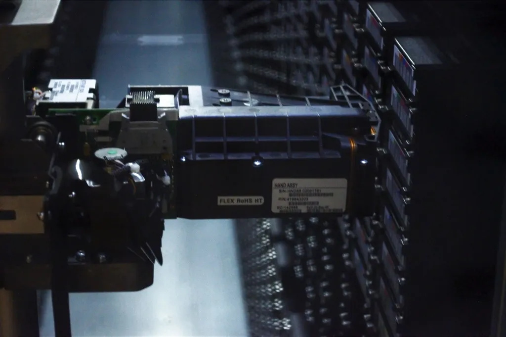 Close-up of a tape library's robotic arm inside a dark data center