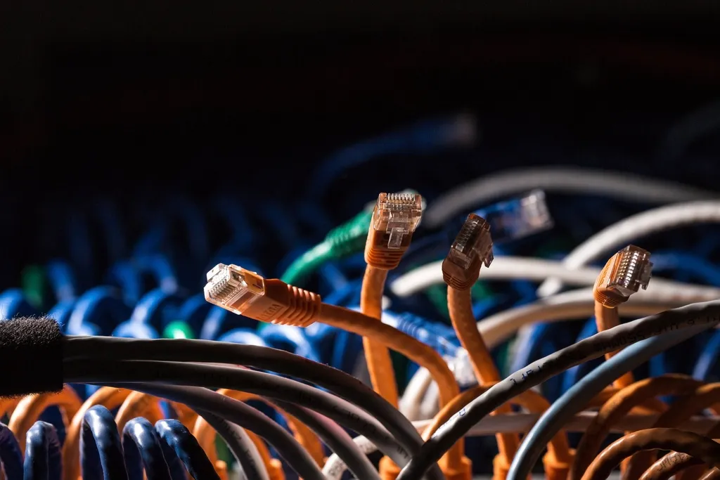 Unplugged orange network cables dangling in front of a dark patch rack