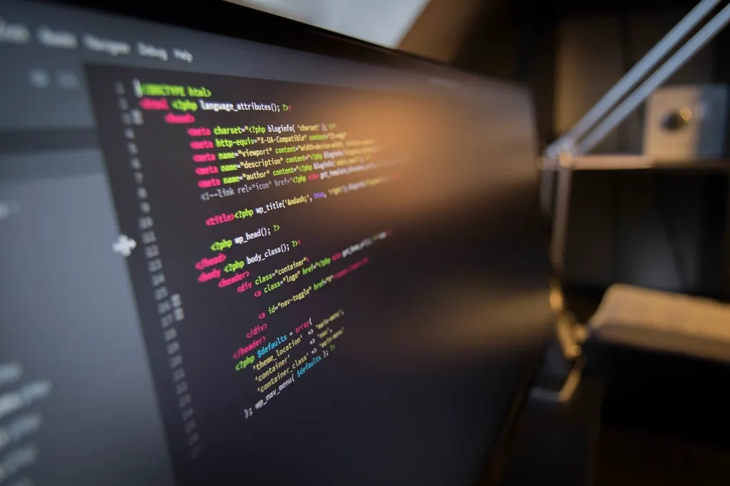 Computer screen seen at an angle, showing colorful code in a dark room