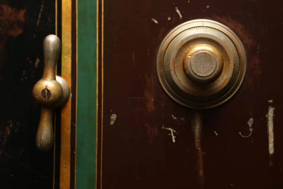 Brass dial of an old safe on a weathered wooden door